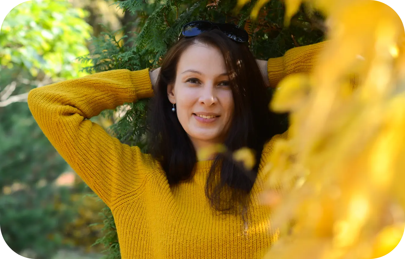 Svitlana Otenko standing by trees with yellow and green leaves